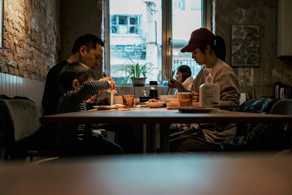 A couple sitting across from each other at a dinner table; one is emotionally engaged, while the other looks disinterested, checking their phone.